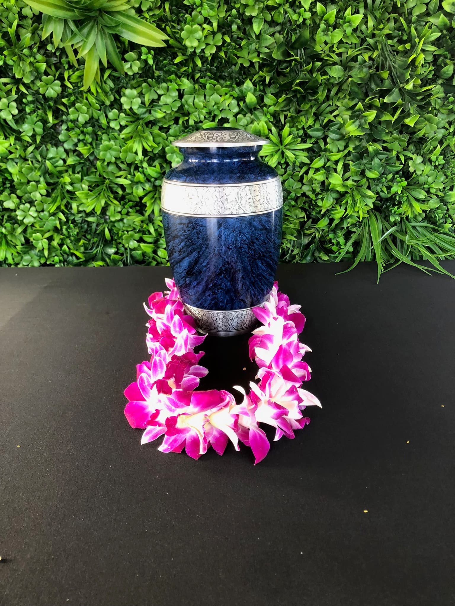 A blue and silver urn set with an orchid lei, prepared ahead of a scattering voyage.